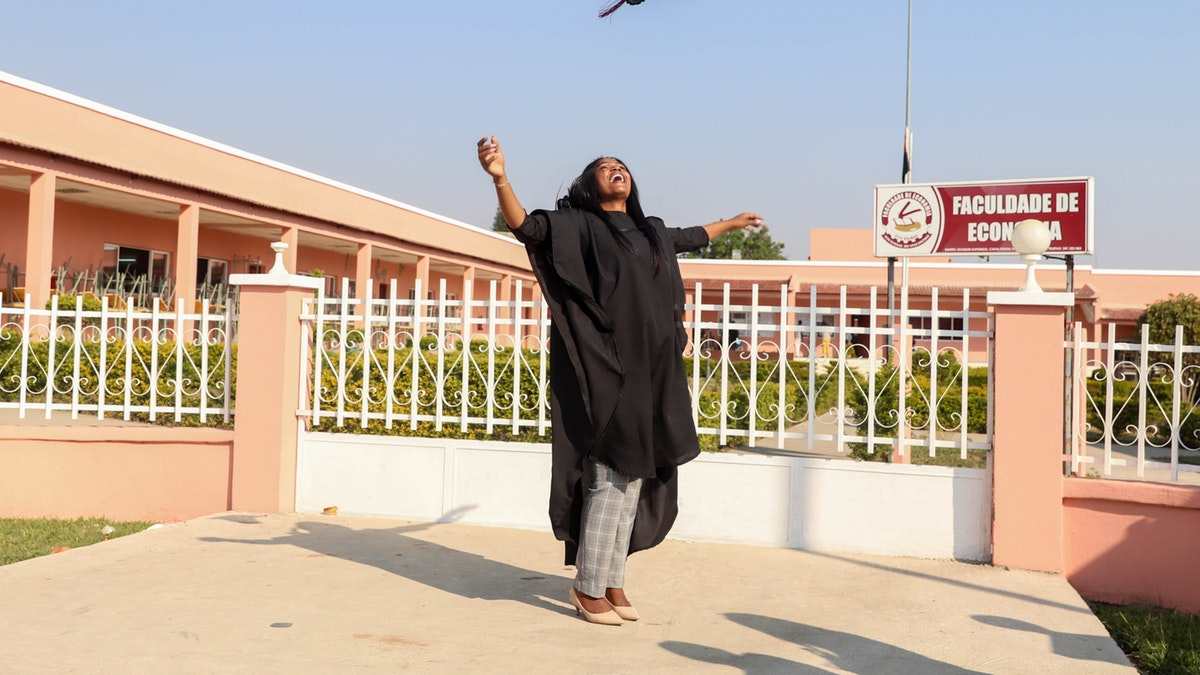 student in a convocation gown tossing her hat